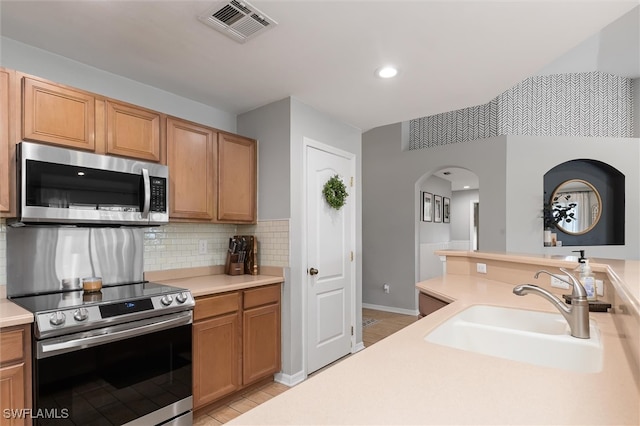 kitchen with sink, appliances with stainless steel finishes, and tasteful backsplash