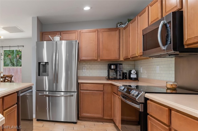 kitchen featuring light wood-type flooring, appliances with stainless steel finishes, and decorative backsplash