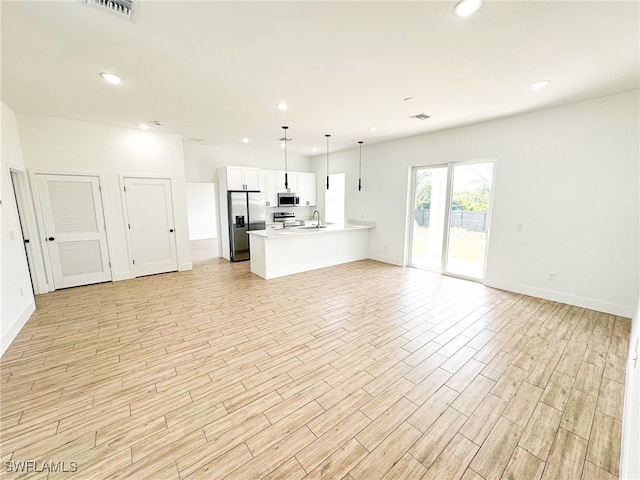 kitchen with decorative light fixtures, light hardwood / wood-style flooring, appliances with stainless steel finishes, sink, and white cabinets