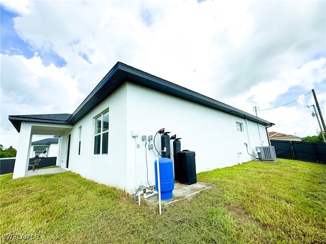 view of side of property featuring central air condition unit, a lawn, and a patio area