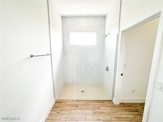 bathroom featuring wood-type flooring and a tile shower