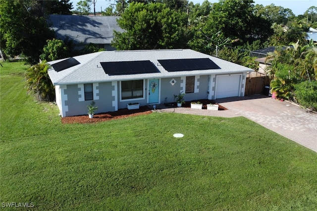 ranch-style house featuring a garage, solar panels, and a front yard