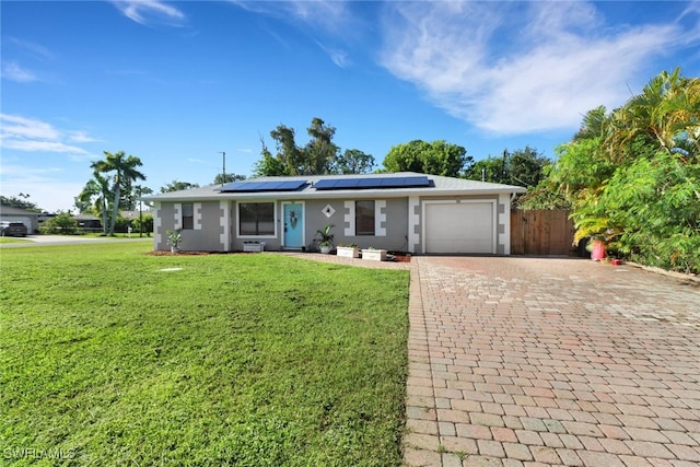 ranch-style house featuring a garage, solar panels, and a front lawn