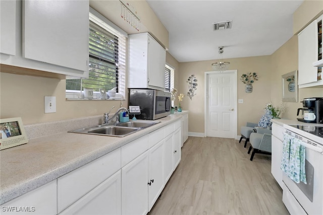 kitchen with hanging light fixtures, sink, white cabinetry, white range oven, and light hardwood / wood-style floors