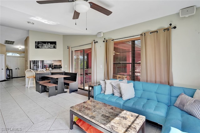 living room featuring ceiling fan, light tile patterned floors, and lofted ceiling