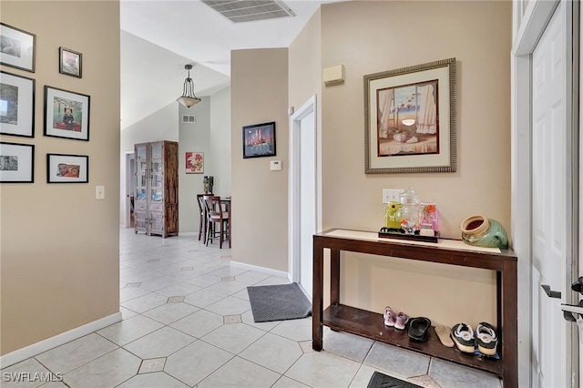 corridor with light tile patterned flooring and vaulted ceiling