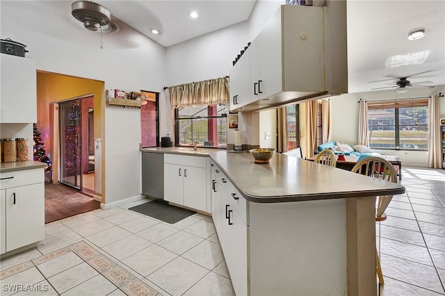 kitchen with white cabinets, kitchen peninsula, stainless steel dishwasher, and ceiling fan