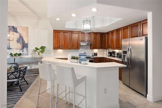 kitchen with appliances with stainless steel finishes, a breakfast bar, backsplash, kitchen peninsula, and a tray ceiling