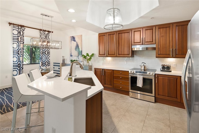 kitchen with pendant lighting, sink, a kitchen breakfast bar, stainless steel appliances, and an inviting chandelier