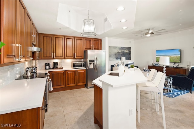 kitchen with pendant lighting, sink, stainless steel appliances, a center island with sink, and ceiling fan