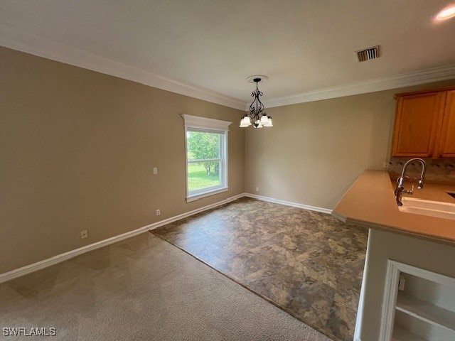 unfurnished dining area with ornamental molding, a chandelier, carpet floors, and sink