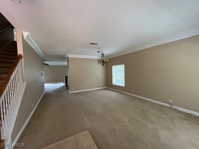 unfurnished living room featuring ornamental molding, light carpet, and a chandelier