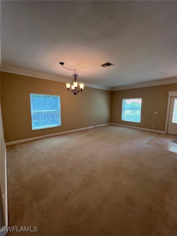 carpeted empty room with ornamental molding and a chandelier