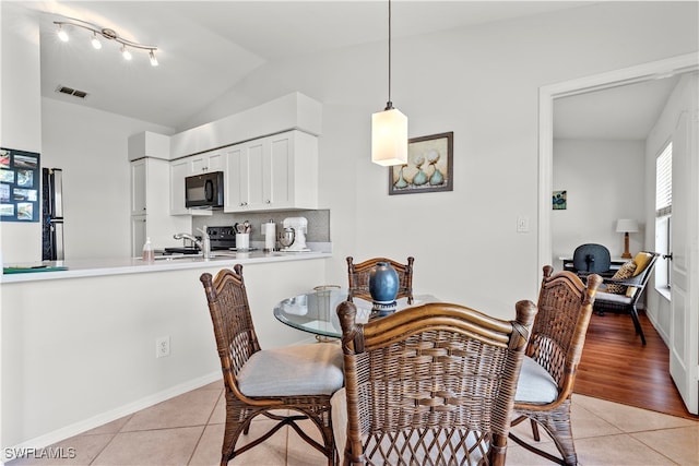 tiled dining area featuring sink and vaulted ceiling