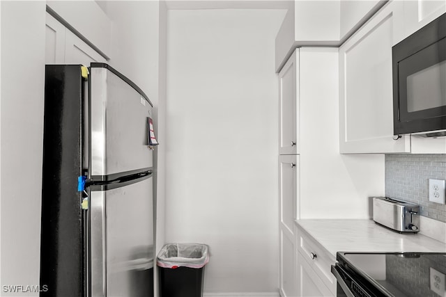 kitchen featuring white cabinets, stainless steel appliances, and decorative backsplash