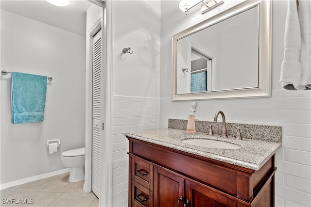 bathroom with tile walls, vanity, toilet, and tile patterned floors