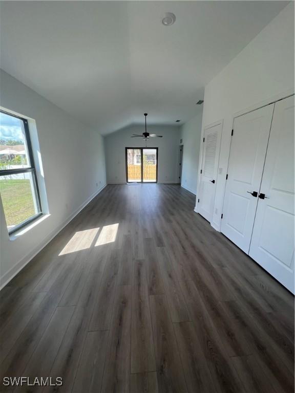 unfurnished living room featuring ceiling fan, dark hardwood / wood-style floors, and vaulted ceiling