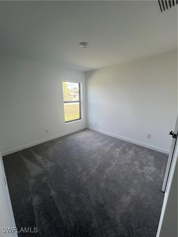 spare room featuring dark colored carpet