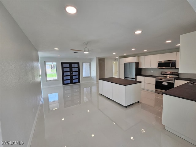 kitchen featuring light tile patterned floors, a center island, appliances with stainless steel finishes, white cabinetry, and ceiling fan