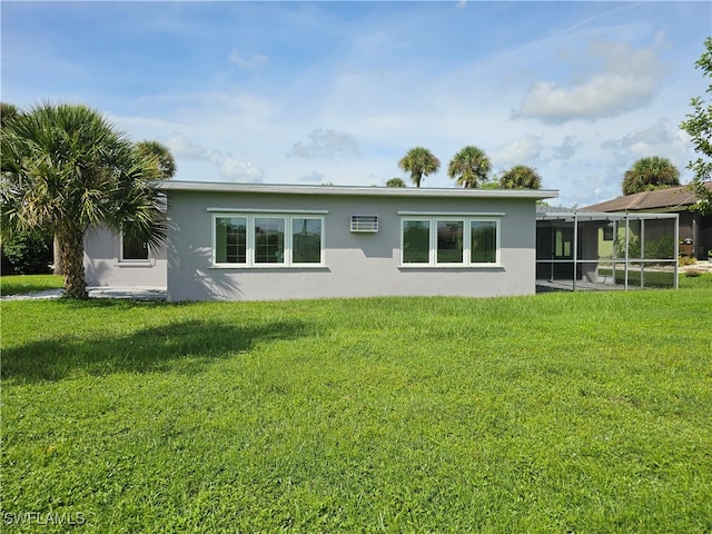 rear view of property featuring a lawn, a wall unit AC, and a sunroom