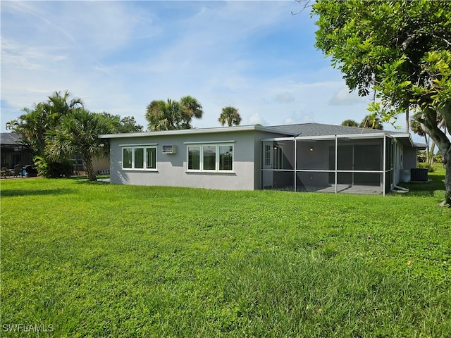 rear view of house with a lawn, a sunroom, and central AC unit