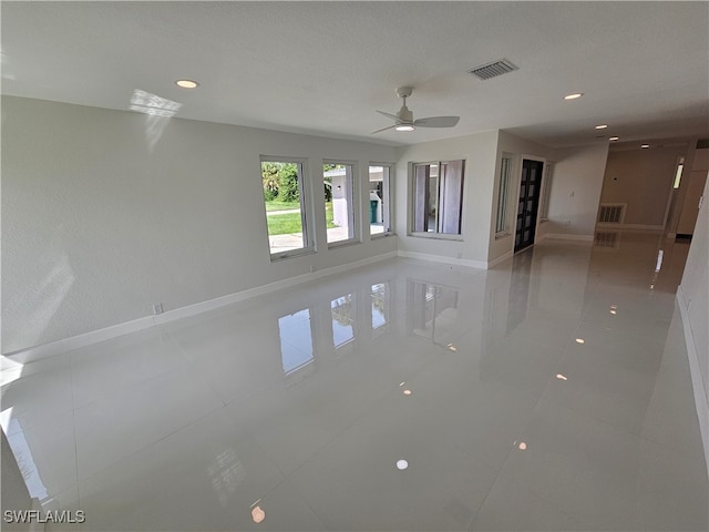 spare room featuring ceiling fan, light tile patterned floors, and a textured ceiling