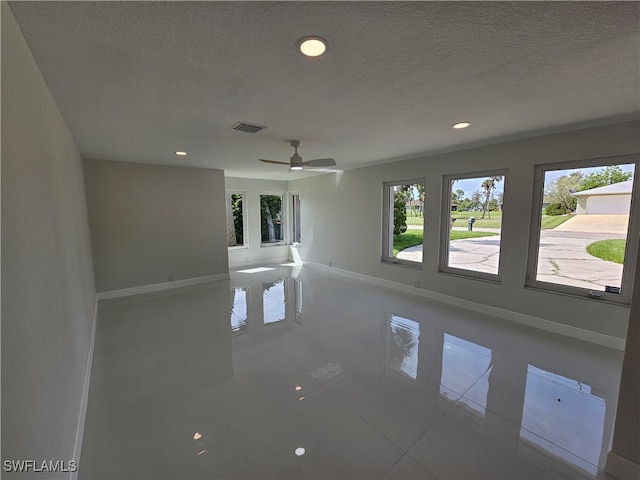 tiled empty room featuring ceiling fan and a textured ceiling