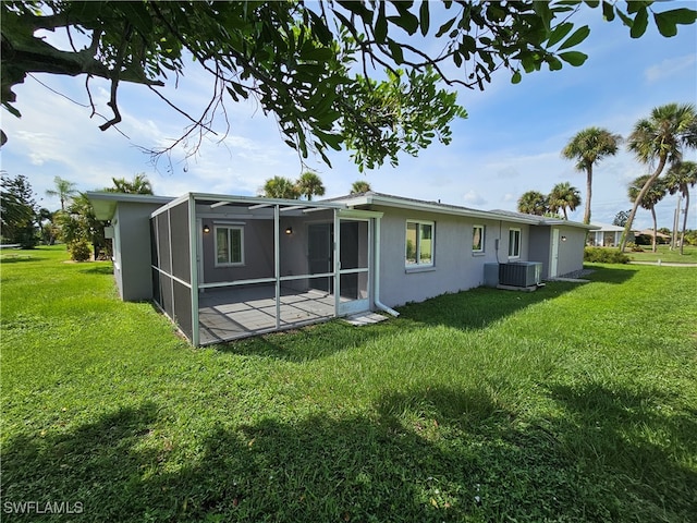 back of property featuring glass enclosure, a yard, and central AC