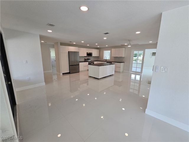 kitchen featuring white cabinetry, light tile patterned floors, a kitchen island, ceiling fan, and appliances with stainless steel finishes