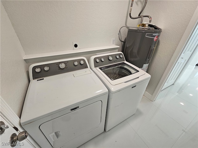 washroom featuring water heater, light tile patterned flooring, and washing machine and dryer