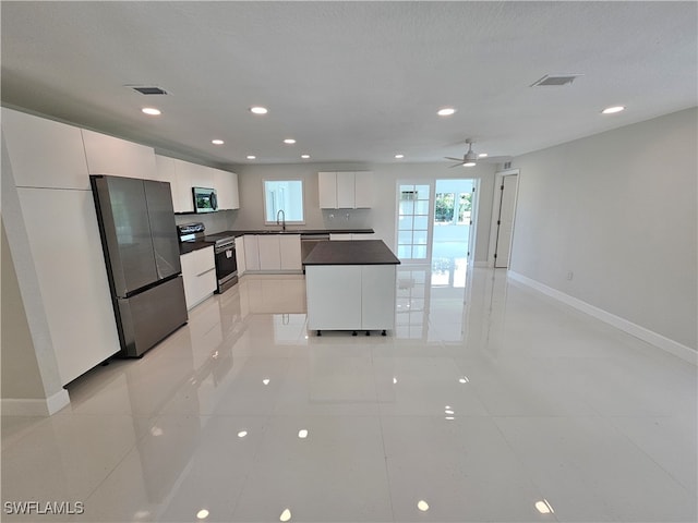 kitchen featuring appliances with stainless steel finishes, light tile patterned floors, ceiling fan, and white cabinets