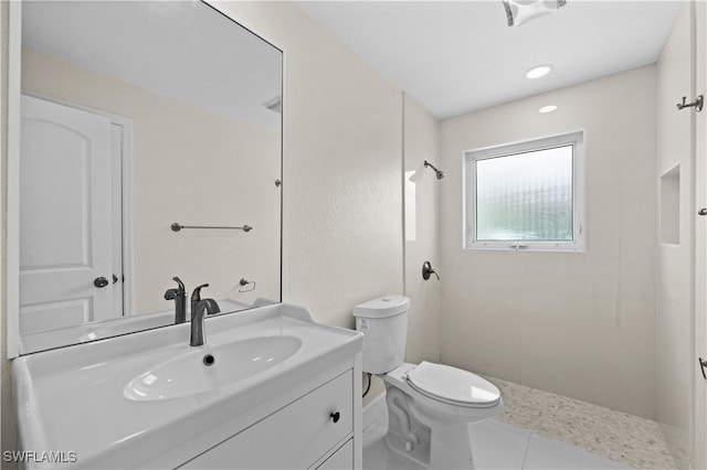 bathroom with vanity, toilet, tiled shower, and tile patterned floors