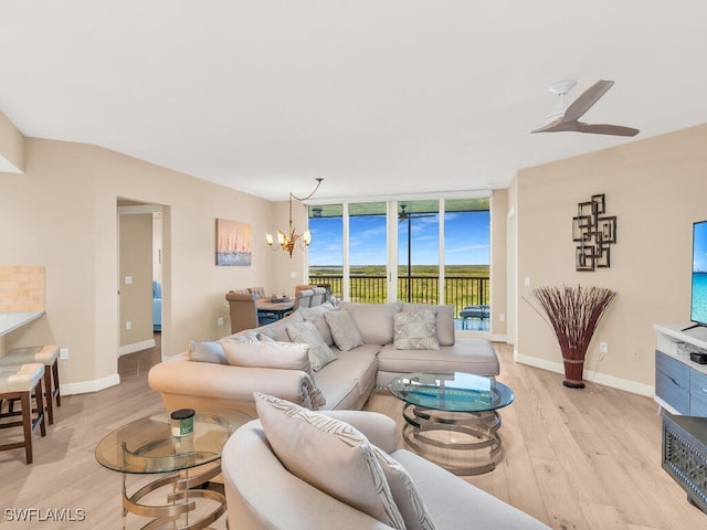 living room with floor to ceiling windows, ceiling fan with notable chandelier, and light wood-type flooring