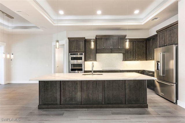 kitchen with a center island with sink, pendant lighting, sink, and appliances with stainless steel finishes