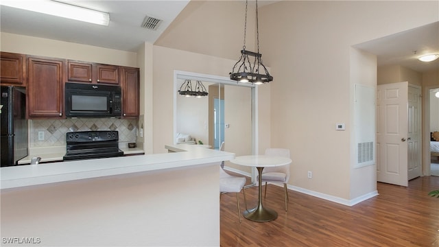 kitchen with pendant lighting, kitchen peninsula, tasteful backsplash, wood-type flooring, and black appliances