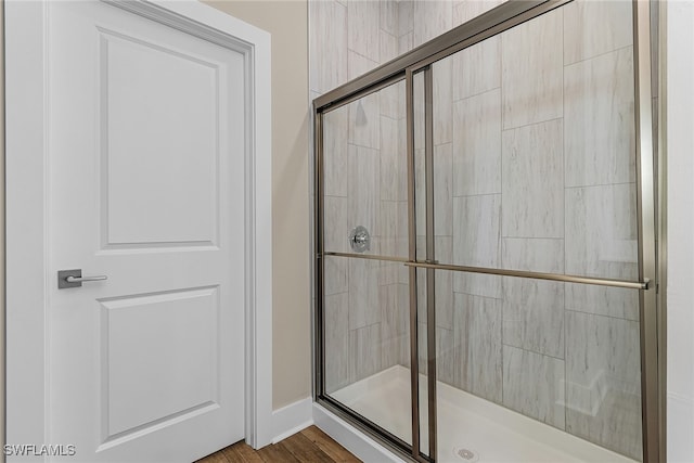 bathroom with hardwood / wood-style flooring and a shower with shower door