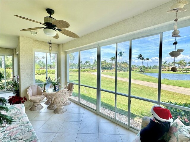 sunroom / solarium featuring ceiling fan and a water view