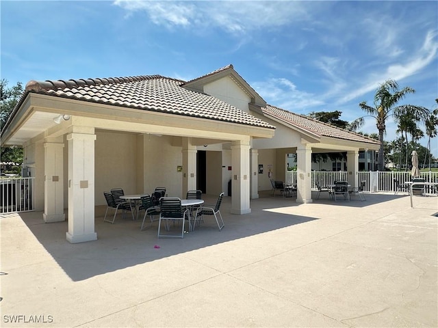 back of property featuring a patio, outdoor dining area, fence, a tiled roof, and stucco siding