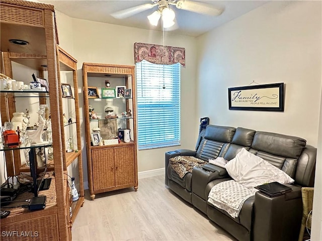 living room featuring light wood-style floors, baseboards, and a ceiling fan