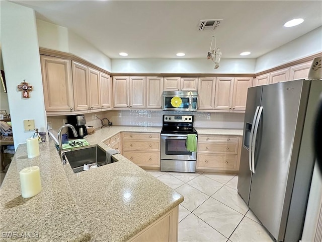 kitchen with appliances with stainless steel finishes, a sink, and light brown cabinetry