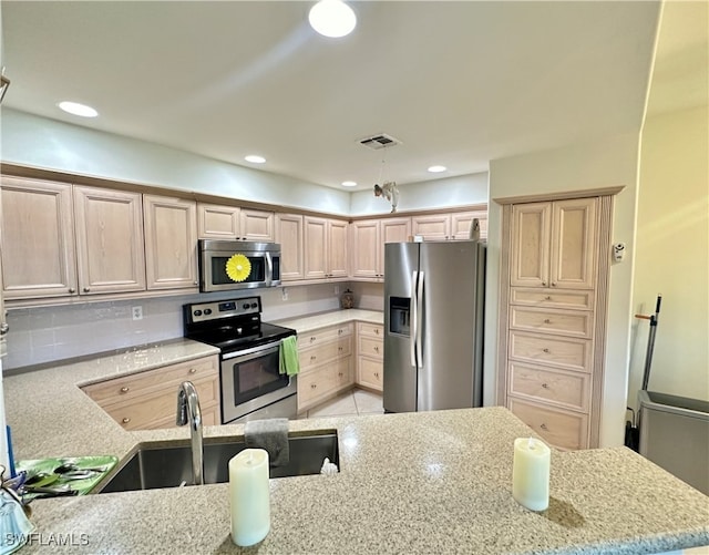 kitchen with light tile patterned flooring, sink, appliances with stainless steel finishes, light stone countertops, and light brown cabinetry