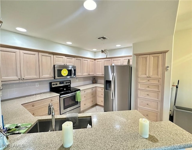 kitchen with visible vents, light stone counters, stainless steel appliances, a sink, and recessed lighting