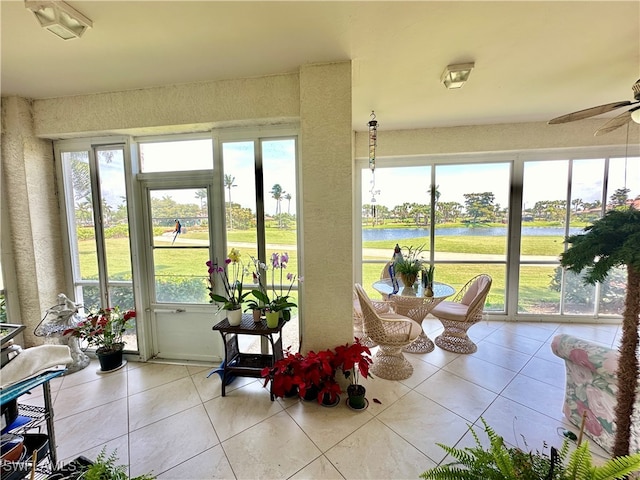 sunroom with a water view and ceiling fan