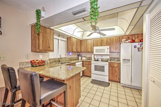 kitchen with white appliances, sink, ceiling fan, kitchen peninsula, and a breakfast bar area