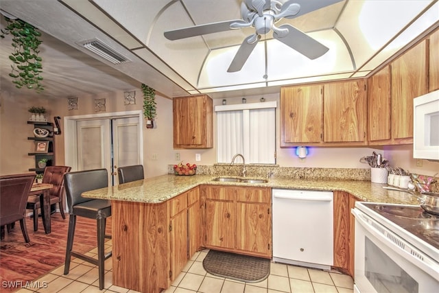 kitchen featuring white appliances, a kitchen bar, kitchen peninsula, sink, and ceiling fan