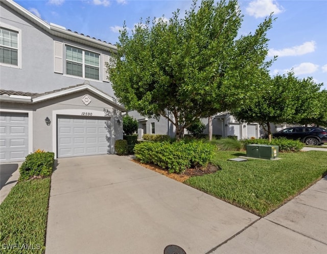 view of front facade with a front yard, a garage, driveway, and stucco siding