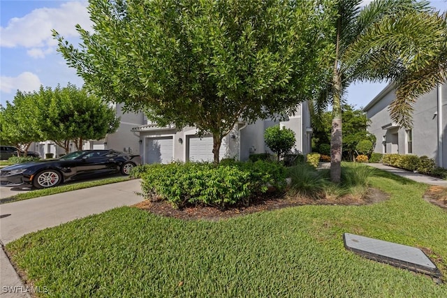 view of front of home with stucco siding, an attached garage, concrete driveway, and a front lawn