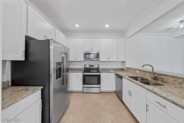 kitchen with appliances with stainless steel finishes, white cabinetry, sink, and light stone countertops