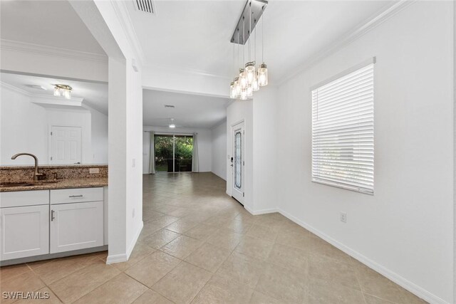 kitchen with light tile patterned floors, sink, decorative light fixtures, and white cabinets