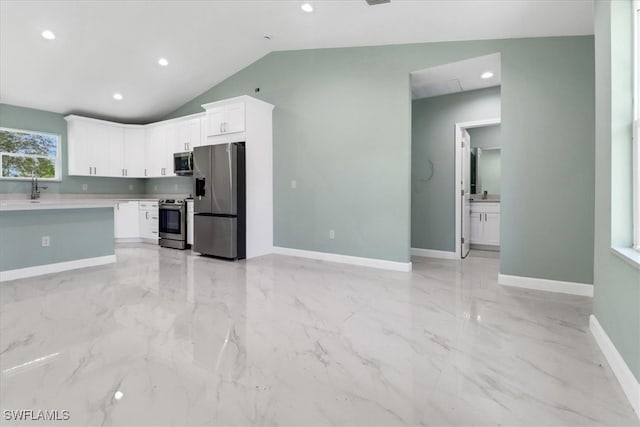 kitchen with stainless steel appliances, lofted ceiling, white cabinets, and sink